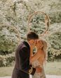 Hula hoop decor for the altar with the bride in a boho lace wedding dress kissing the groom in military uniform. 