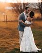 Bride in floral lace wedding dress with groom in grey suit share a kiss before their mariachi band wedding entertainment.
