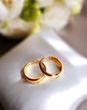Close up of two wedding rings, placed on a cushion, highlighting marriage