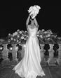 Black and white photo of a bride in a floor-length wedding dress holding a bouquet raised in the air.
