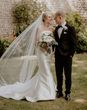 Mermaid wedding dress worn by the bride standing with groom in black tux