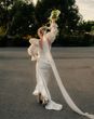 Bride wearing vintage style puff sleeve wedding dress holding bouquet in the air