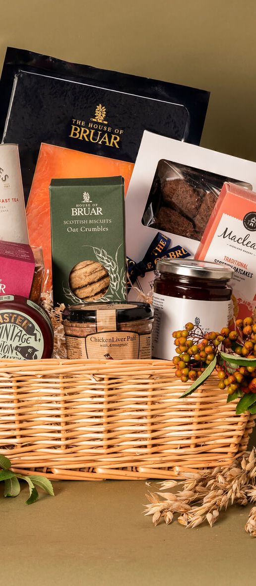 House of Bruar Classic Hamper filled with luxury Scottish produce including smoked salmon, cheese, preserves, chocolates, biscuits, tea, and wine, presented in a wicker basket.