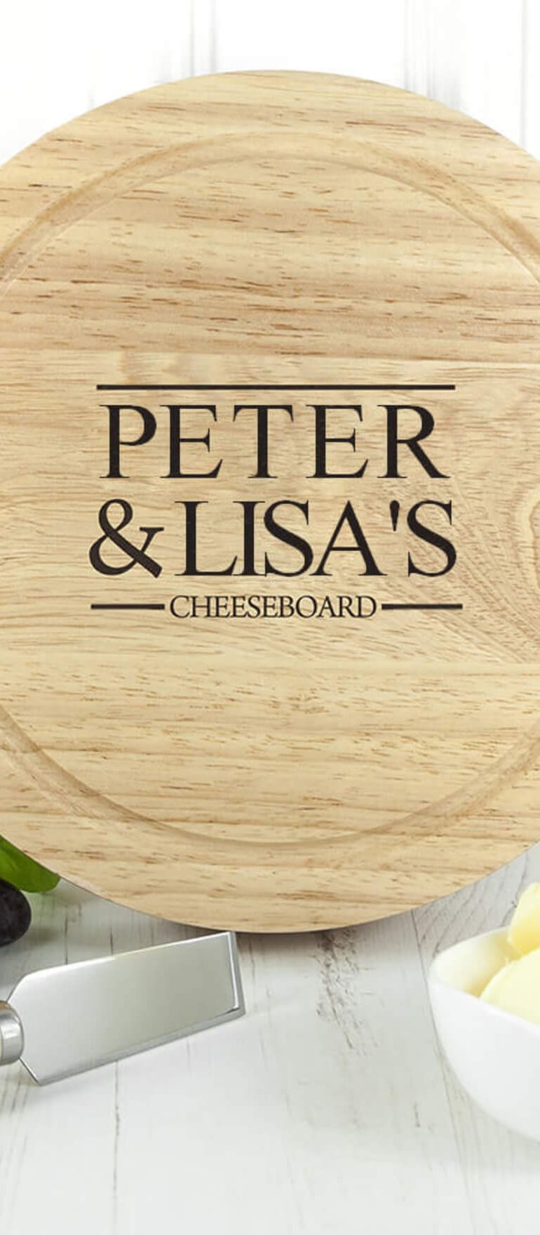 Personalised wooden cheeseboard engraved with Peter and Lisa's names, displayed with cheese, grapes, and a cheese knife – a unique wedding gift idea