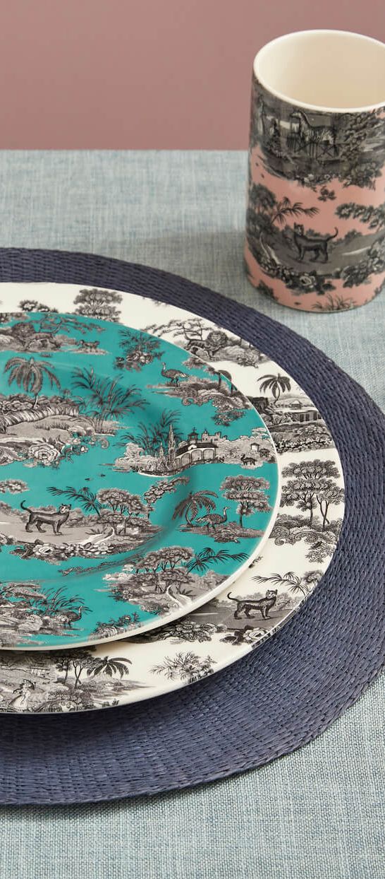 Spode Zoological Gardens 12-piece dinnerware set with vibrant patterned plates and mug, styled on a table setting with flowers and gold cutlery