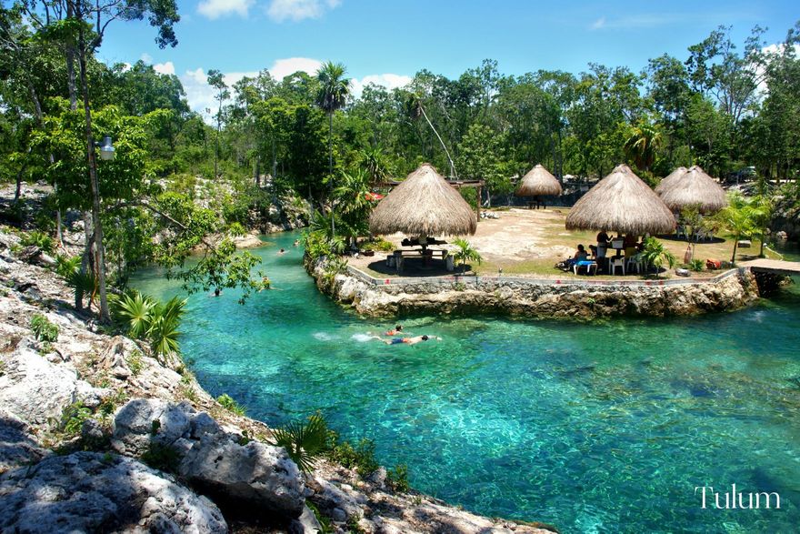 Boho style setting in Tulum with natural swimming lake, palm trees and straw huts for Mexico honeymoon