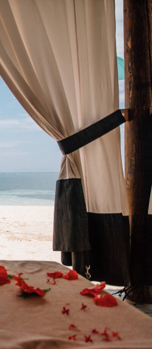 Couple enjoying a romantic Caribbean honeymoon at a Sandals Resorts beach cabana, with champagne, flower petals and ocean views