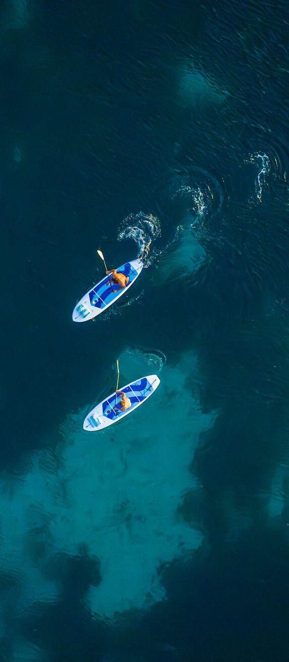 Couple paddleboarding in clear Caribbean sea during their Sandals Resorts honeymoon