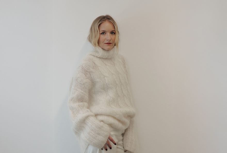 Hermione Olivia, standing all in white against a white wall