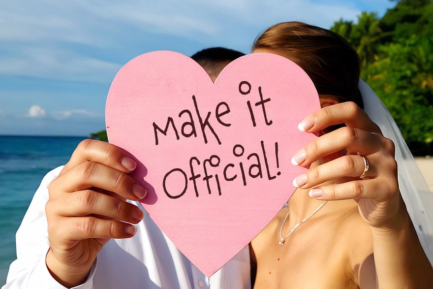 couple holding up 'make it official' sign on a beach wedding
