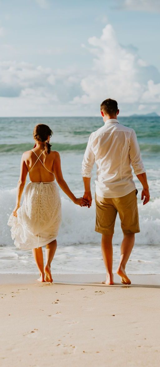 Couple holding hands by the sea on their honeymoon