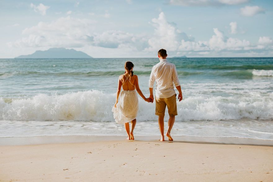 Couple holding hands by the sea on their honeymoon