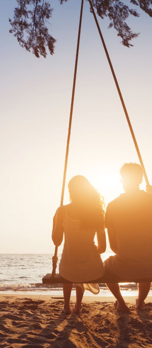 Couple on a shared beach swing on their honeymoon