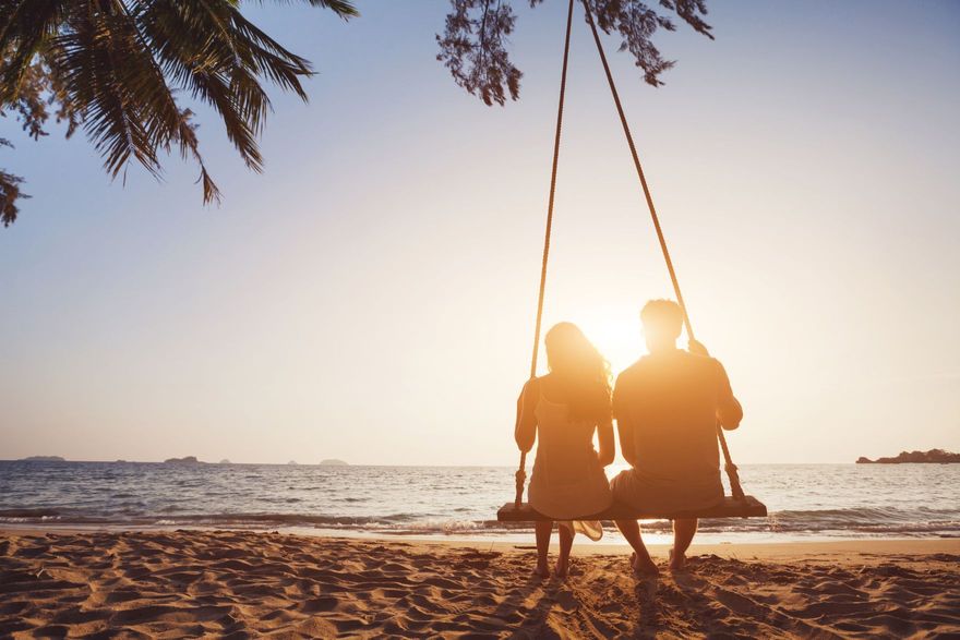 Couple on a shared beach swing on their honeymoon
