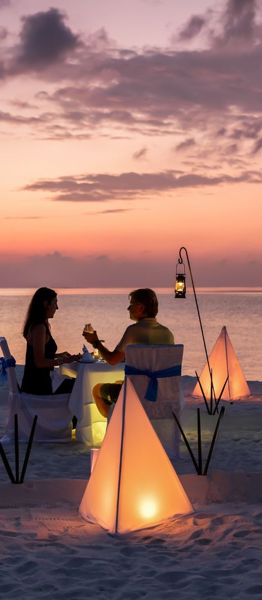 Couple having romantic beach sunset dinner on their honeymoon