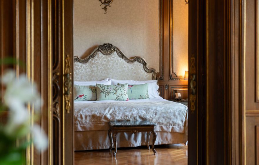 Luxury bedroom inside the Royal Suite at Hostal de La Gavina, featuring ornate wood panelling, antique furnishings and classic European design.
