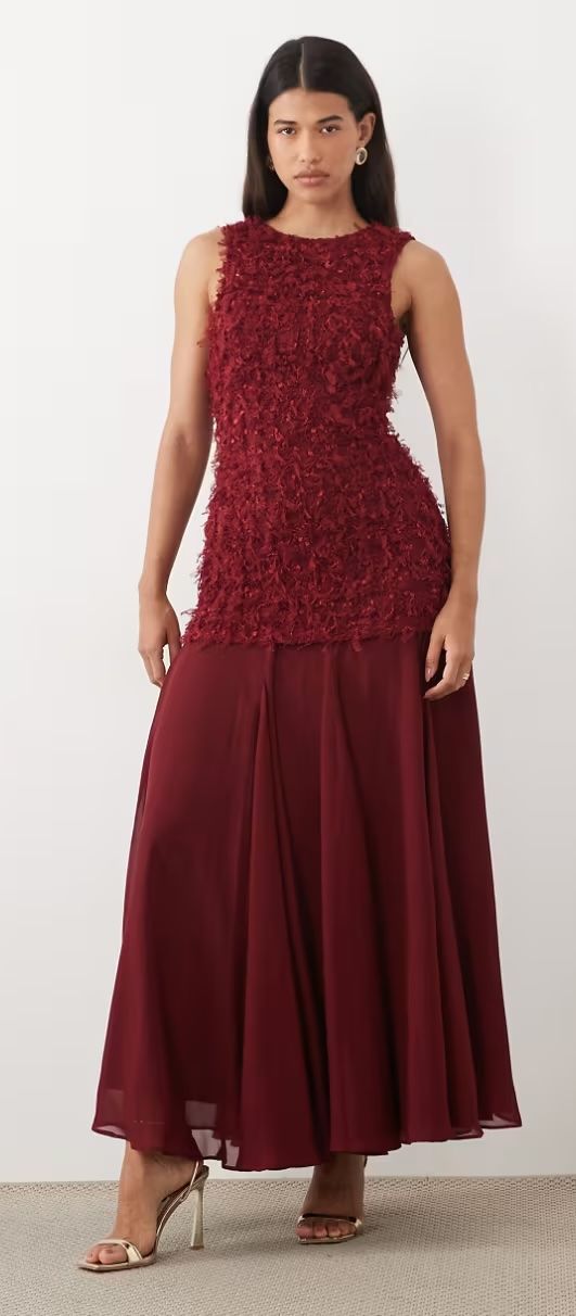 Model wearing a burgundy sleeveless maxi dress with textured bodice and flowing chiffon skirt