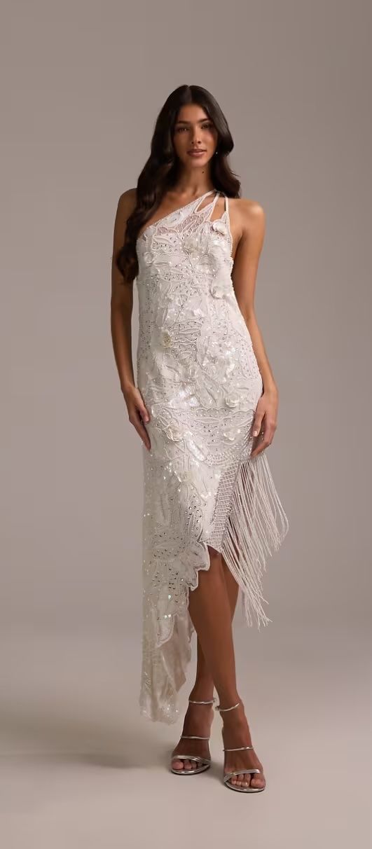 Bride in an asymmetric one-shoulder embellished dress with fringed hem and silver heels