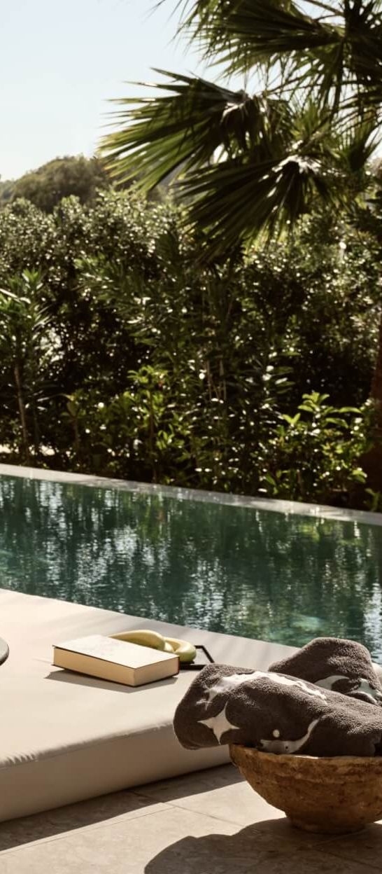  Private pool suite terrace at Asterion Suites & Spa in Crete, featuring a luxury daybed, outdoor seating and direct access to a tranquil swim-up pool surrounded by tropical gardens.