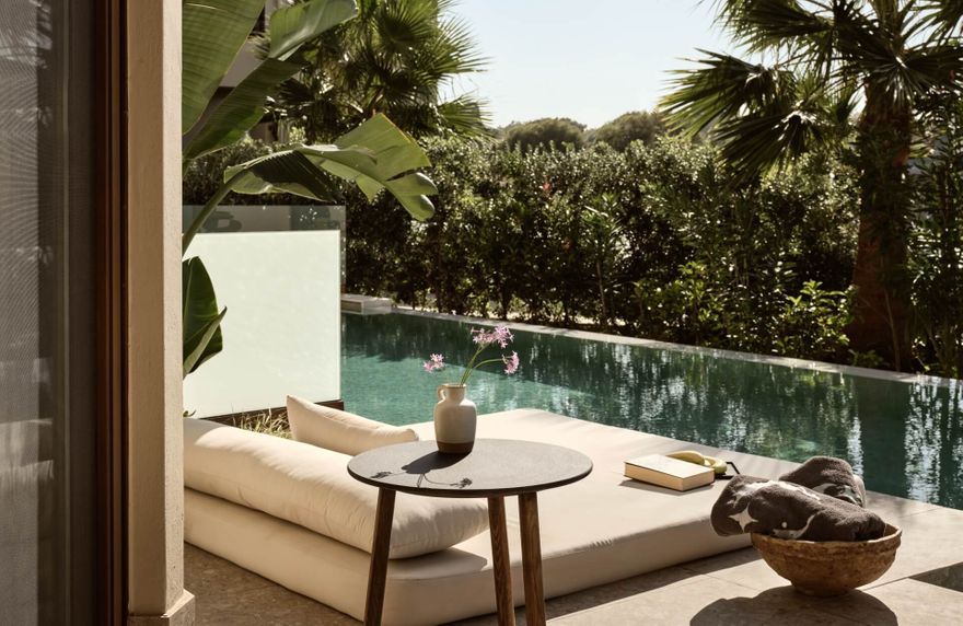 Private pool suite terrace at Asterion Suites & Spa in Crete, featuring a luxury daybed, outdoor seating and direct access to a tranquil swim-up pool surrounded by tropical gardens.