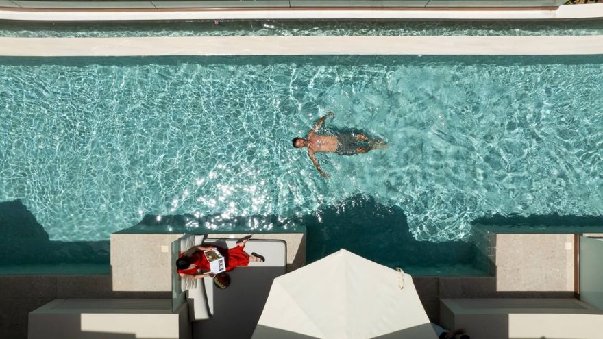 Aerial view of a couple enjoying a private swim-up suite at Asterion Suites & Spa in Crete, featuring a luxury pool, sun lounger and contemporary outdoor terrace.