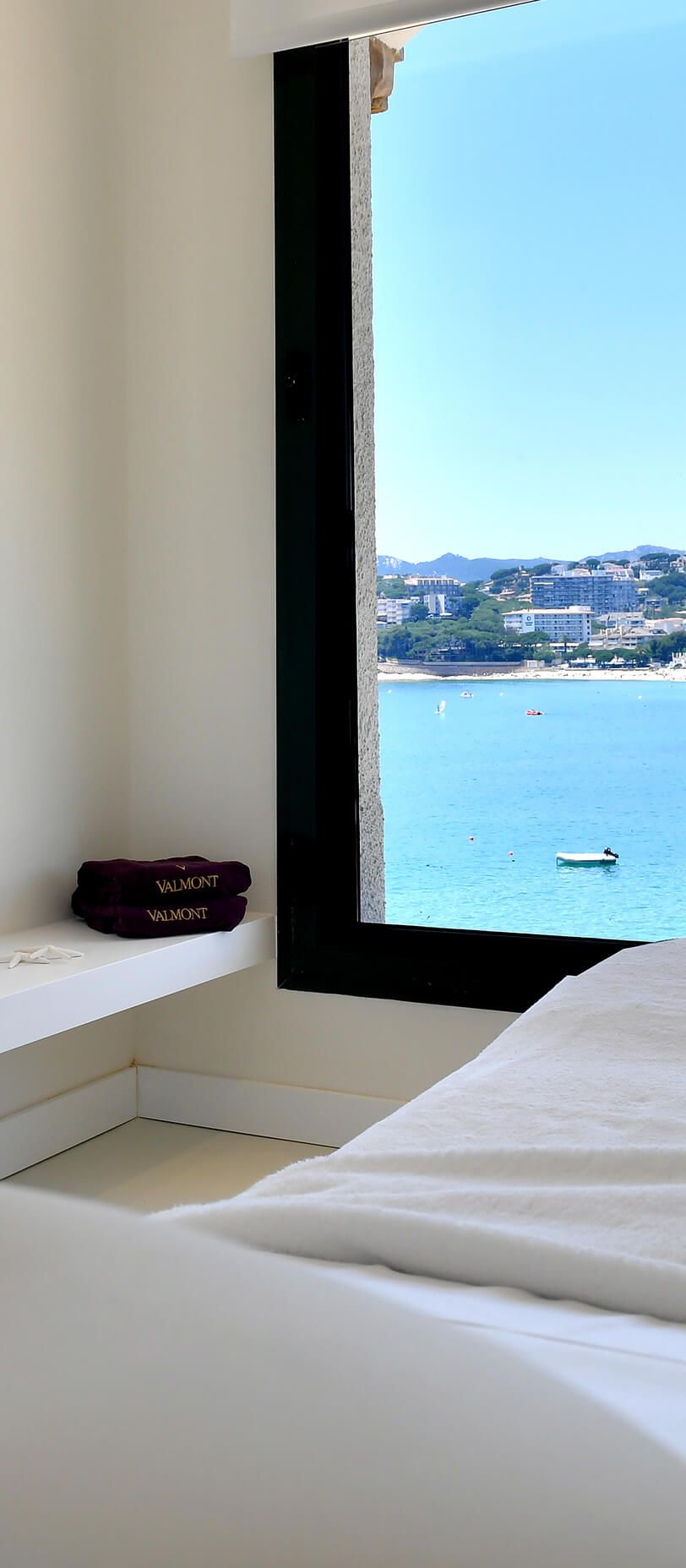 Valmont Spa treatment room at Hostal de La Gavina in Costa Brava, featuring a massage bed overlooking the Mediterranean Sea through a large picture window, creating a peaceful luxury wellness experience for honeymoon couples.