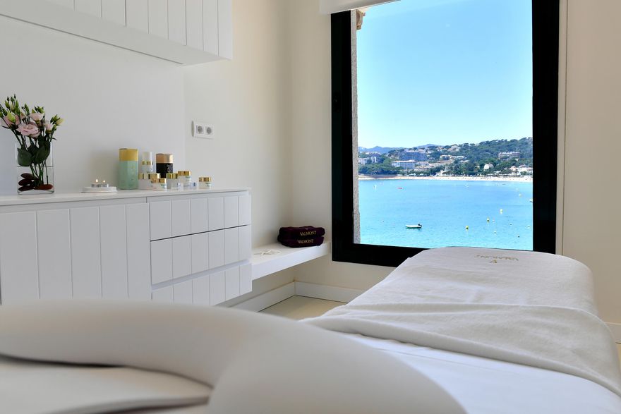 Valmont Spa treatment room at Hostal de La Gavina in Costa Brava, featuring a massage bed overlooking the Mediterranean Sea through a large picture window, creating a peaceful luxury wellness experience for honeymoon couples.